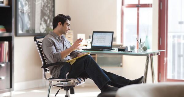 Person sitting at a standing desk setup in a bright office